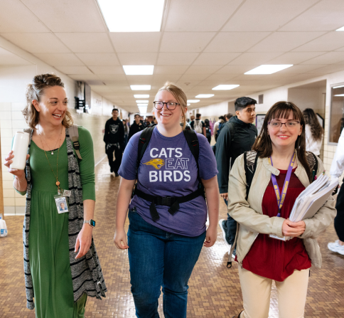 Group of individuals walking down a crowded hallway.
