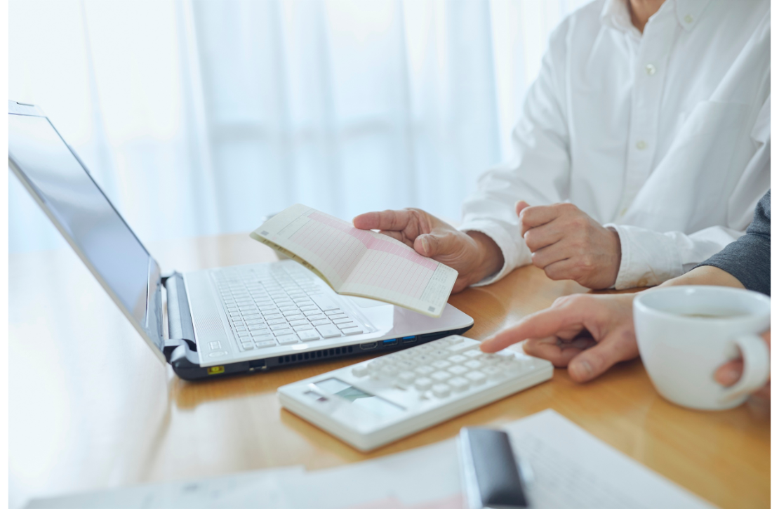 Two people working with a laptop and calculator.